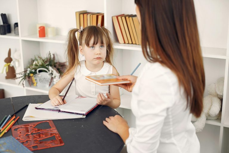 Cute schoolchild doing homework with help of tutor