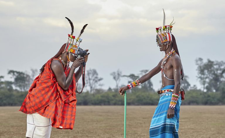 A Man Taking Photo of a Man in Blue Traditional Clothing