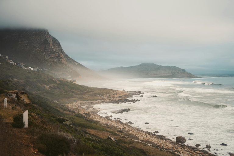 A serene view of Cape Town's coastline with misty cliffs and crashing waves.