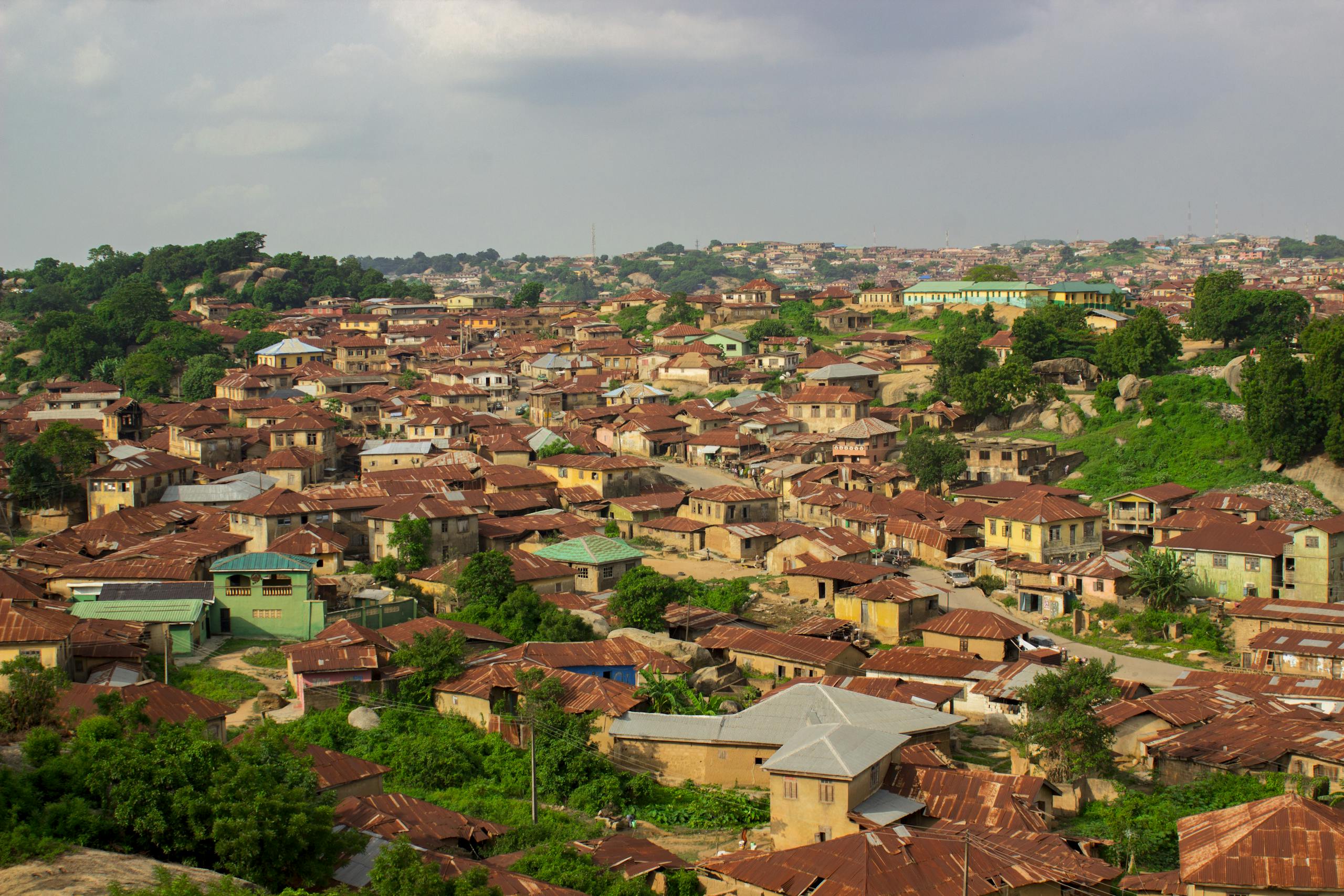 Aerial view of rustic rooftops in Abeokuta, Nigeria with greenery.